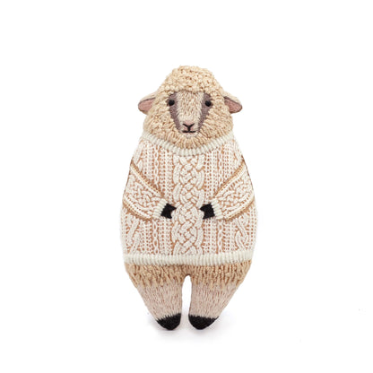 Knitted sheep toy wearing a sweater on a white background
