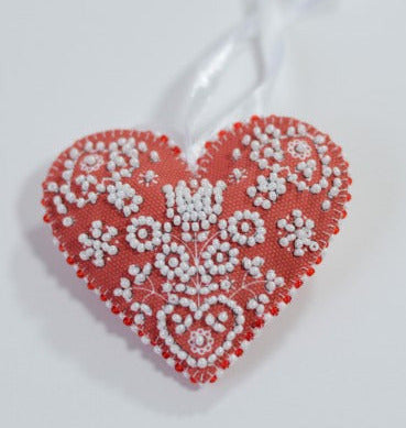 Decorative heart ornament with white floral patterns on a light gray background