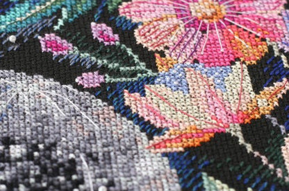 Close-up of cross-stitched flowers with colorful threads on a black fabric background