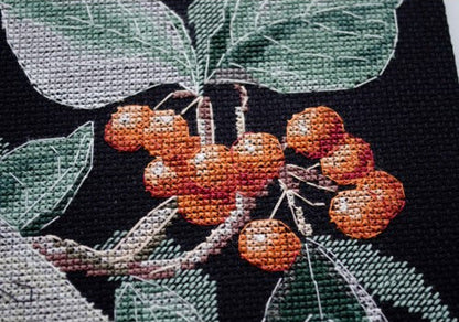 Cross-stitched design of berries and leaves on black fabric