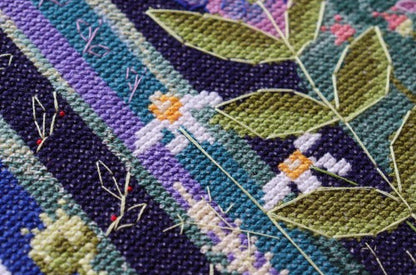 Close-up of a cross-stitched piece with leaves and flowers on a striped background
