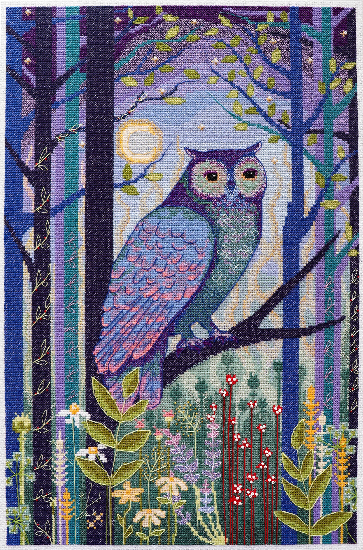 Embroidered design of an owl in a forest with trees and flowers.